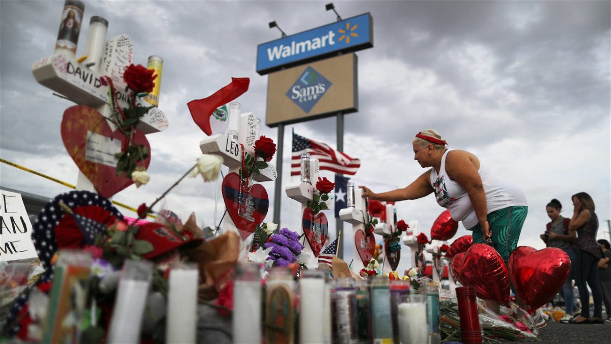 A woman touches a cross at a makeshift memorial for victims outside Walmart, near the scene of a mass shooting on Aug. 3, 2019, which left dozens of people dead in El Paso.