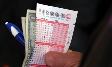 Holding Powerball ticket with cash