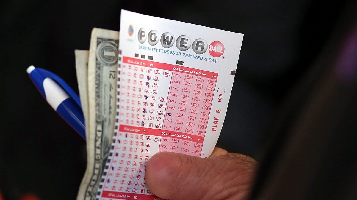 A man holds his Powerball number selections in his hand along with cash to buy tickets.