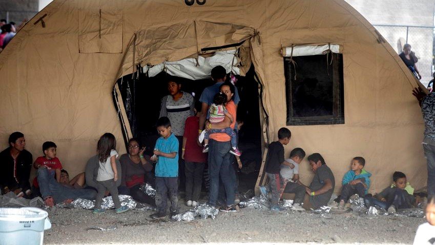 Families outside a tent at a temporary migrant holding area set up by Customs and Border Protection under the Paso del Norte International Port of Entry between Juarez and El Paso.