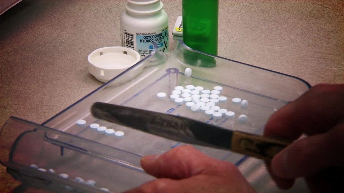 A pharmacist handles opioid pills.