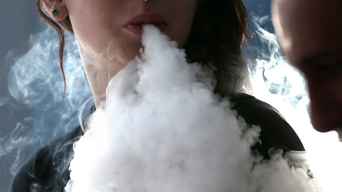 A woman is seen exhaling while vaping.