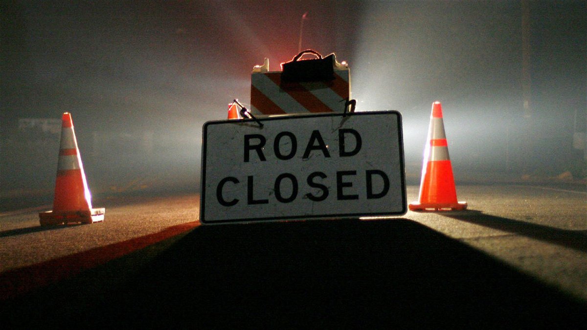 A road closed sign is illuminated at night.