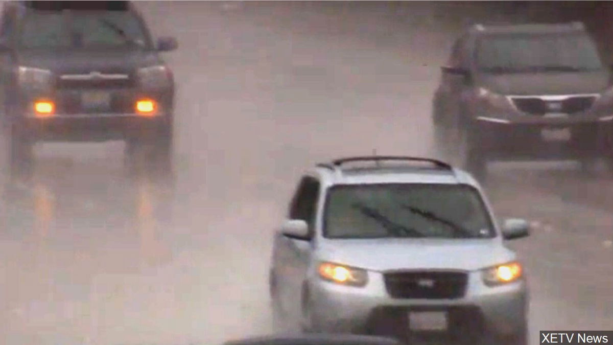 Motorists navigate wet roads in a pouring rain.