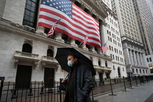 A man wearing a mask walks by the New York Stock Exchange building in New York.