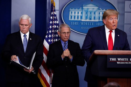 VP Mike Pence and Dr. Anthony Fauci listen as President Trump speaks at the podium.