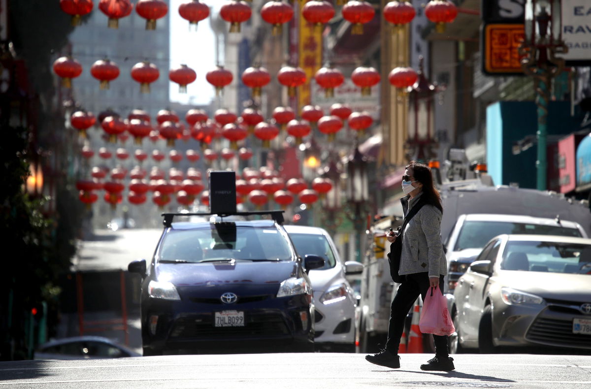 People wear masks as they walk along Chinatown's Grant Avenue in San Francisco, California.