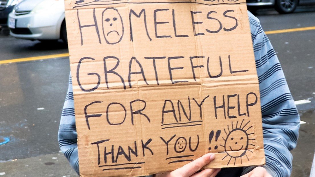 A homeless man holds a sign seeking help in this file photo.