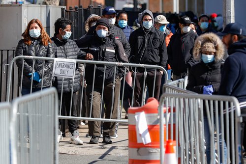 Patients wearing face masks and personal protective equipment wait on line for COVID-19 testing outside Elmhurst Hospital Center in New York.