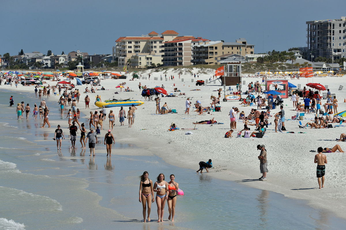 Students gather along a beach during Spring Break.
