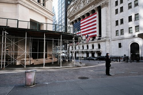 A largely deserted Wall Street near the New York Stock Exchange building, which is draped with an American flag.
