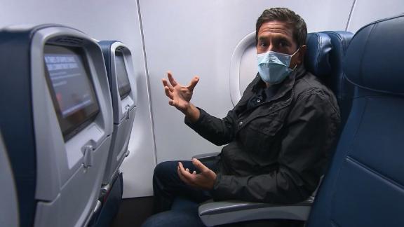 An air traveler wearing a mask takes his seat after boarding a plane.