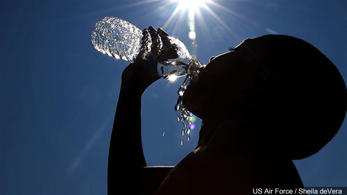 A woman stays hydrated under the hot Texas sun by drinking water.