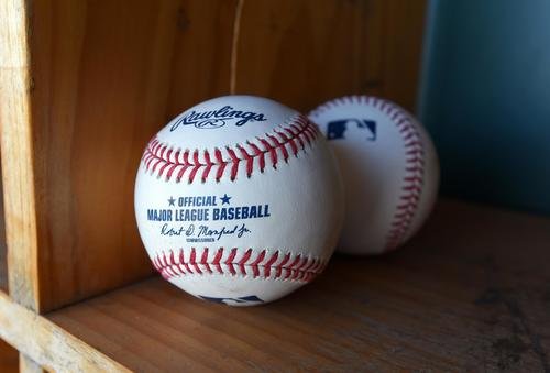 MLB baseballs sit on a shelf.