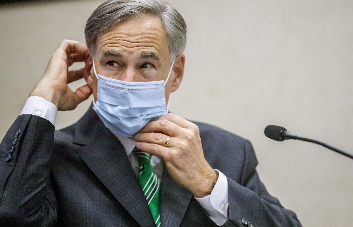 Texas Gov. Greg Abbott adjusts his face mask during a past briefing with reporters.
