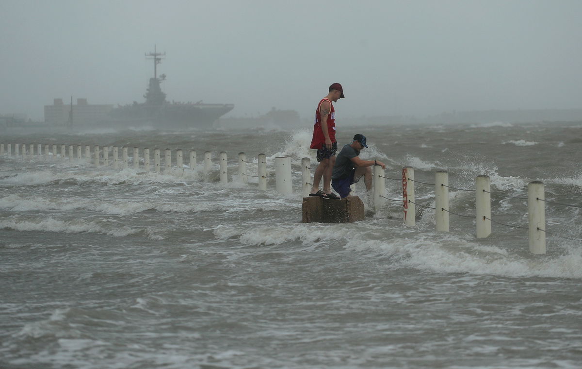 Two men stand near a sea wall as Hurricane Hanna makes landfall in Corpus Christi, Texas. 