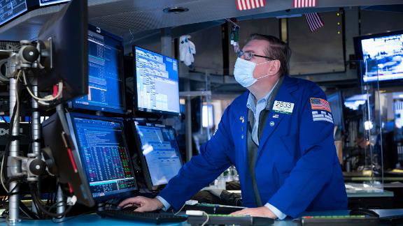 A trader wears a mask as he monitors the New York Stock Exchange.