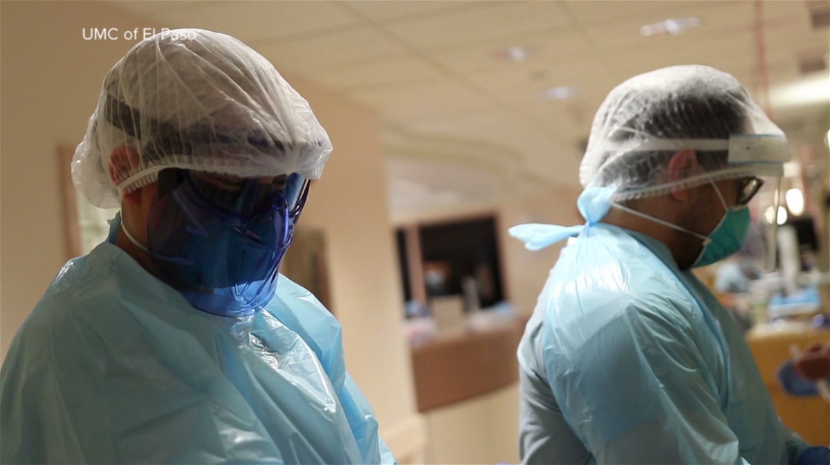 Two healthcare workers put on personal protective equipment inside University Medical Center's Covid unit.
