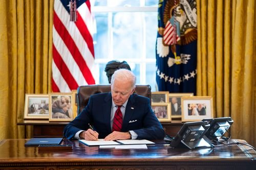 President Biden signs an executive order in the Oval Office.