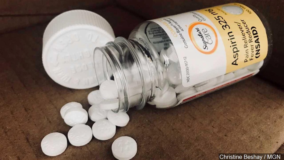 An aspirin bottle and pills are seen on a counter top.