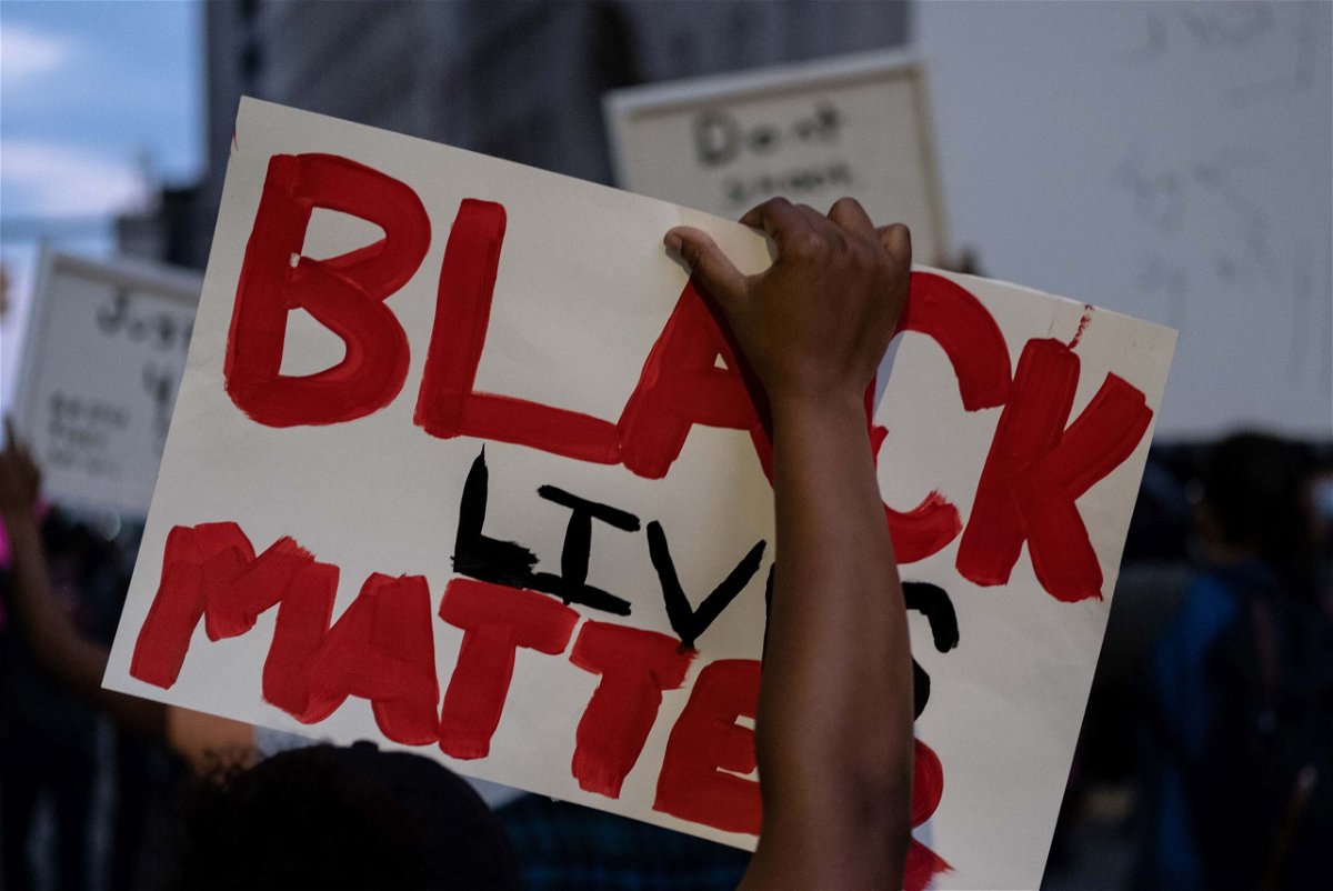 A person holds up a placard that reads, 'Black lives matter' during a protest.