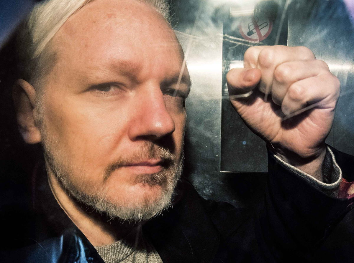 WikiLeaks founder Julian Assange gestures from the window of a van as he is driven into London for a court hearing.