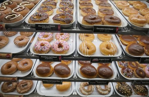 Krispy Kreme donuts are displayed on bakery case shelves.