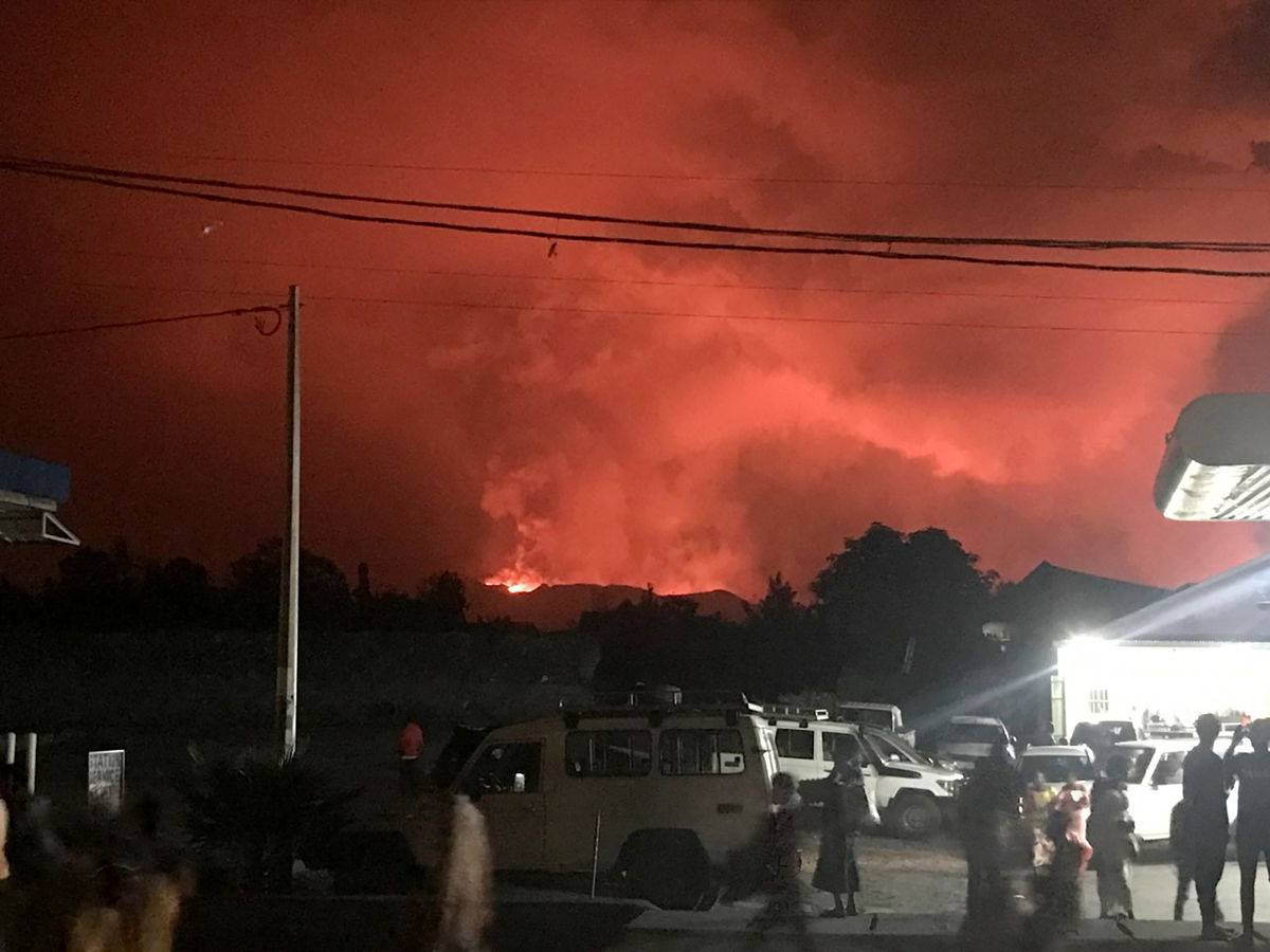 Civilians watching the smoke and flames of the volcanic eruption near Goma, Democratic Republic of Congo.