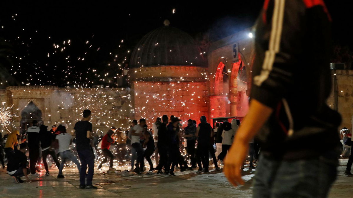 Palestinian protesters hurl rocks amid stun grenade sparks during clashes with Israeli security forces at the al-Aqsa mosque compound in Jerusalem.