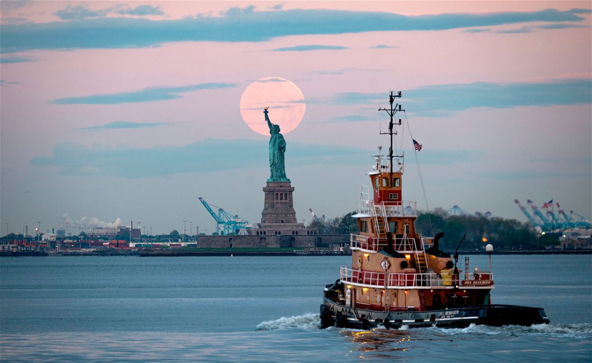 May's full Moon, known as the Full Flower Moon and is the last supermoon of the year, sets behind the Statue of Liberty on May 7, 2020 in New York City.