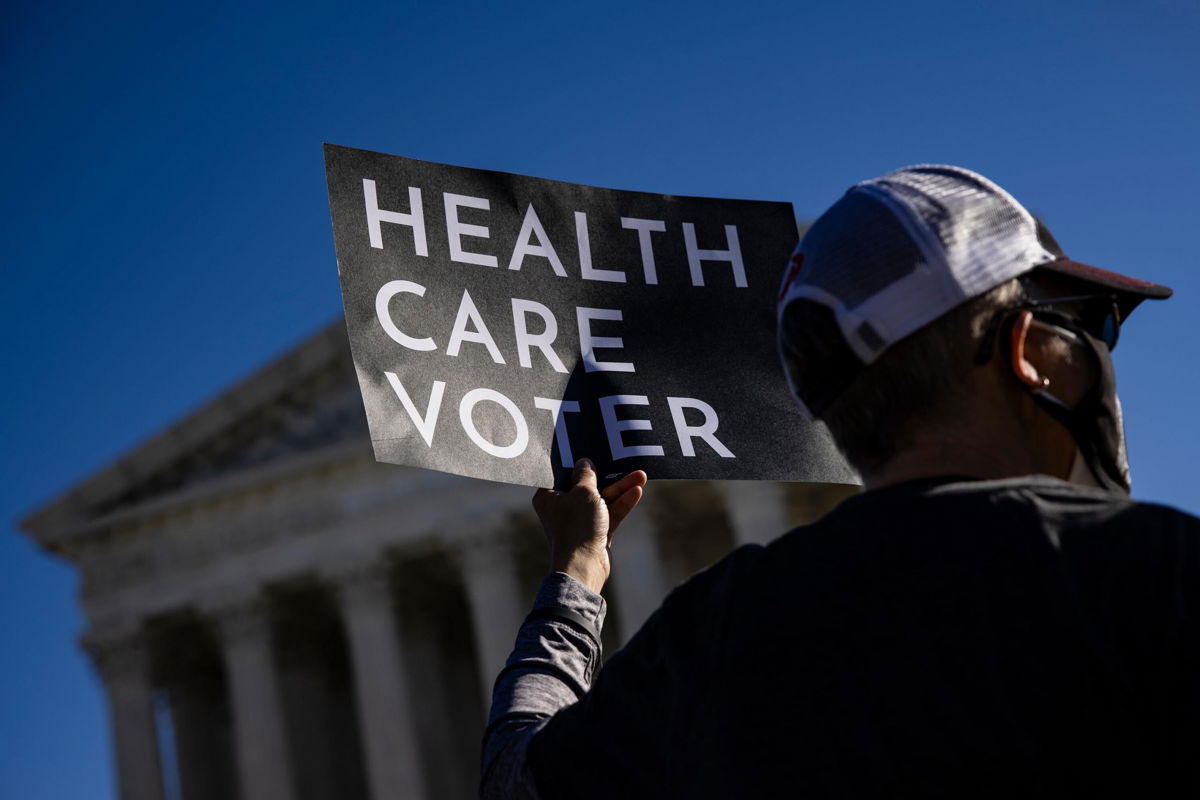 A health care voter holds a sign in front of the U.S. Supreme Court building.