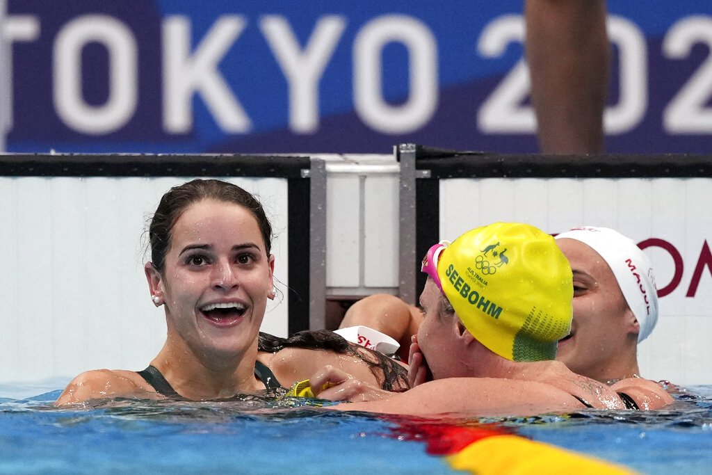 Kaylee McKeown, left, of Australia is congratulated by compatriot Emily Seebohm and Canada's Kylie Masse, right, after winning the final of the women's 100-meter backstroke.