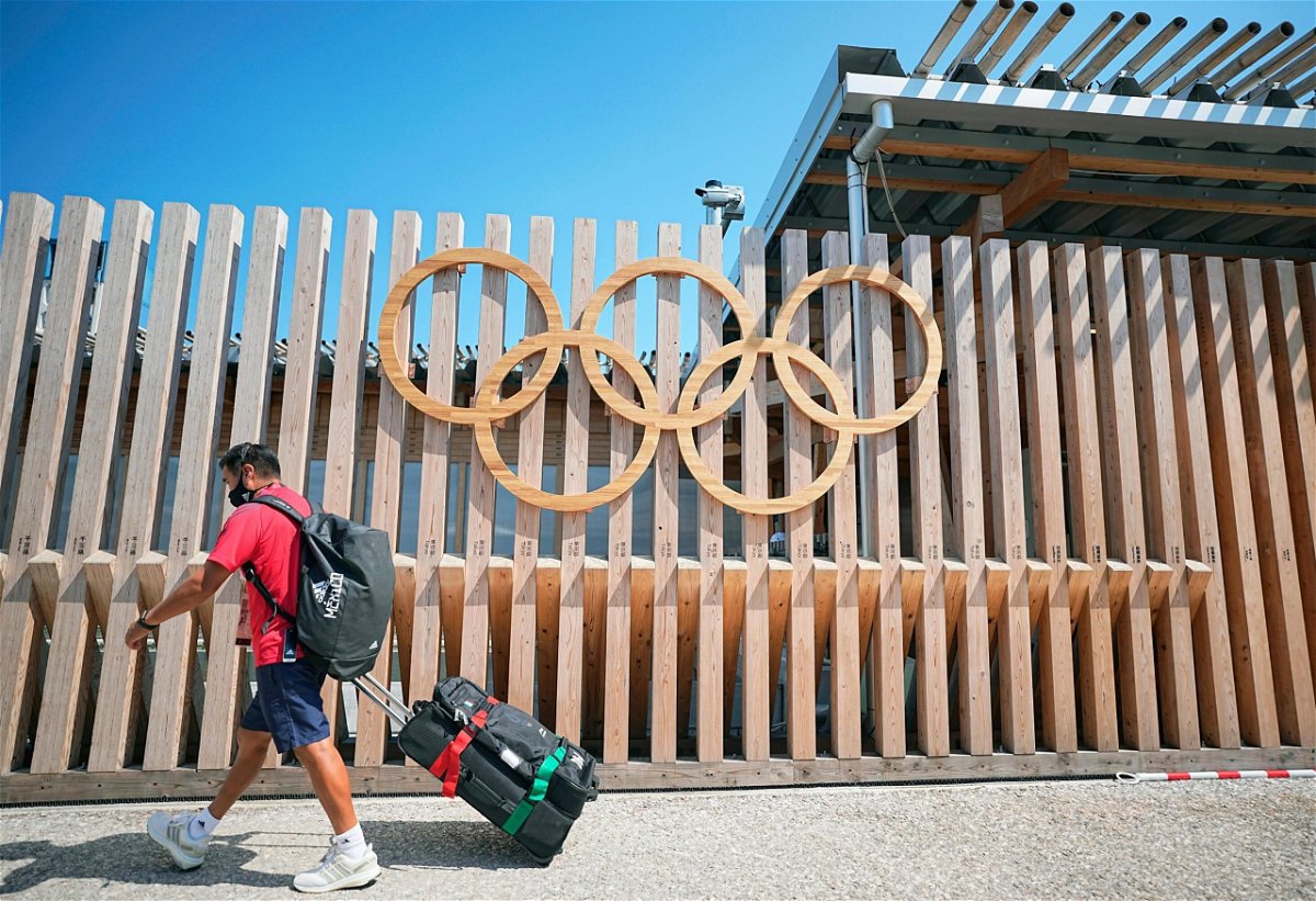 <i>Michael Kappeler/picture-alliance/dpa/AP</i><br/>A member of the Mexican delegation walks past Olympic rings at the entrance to Olympic Village. The sports world