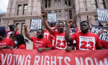 A group joins a rally to support voter rights on the steps of the Texas Capitol