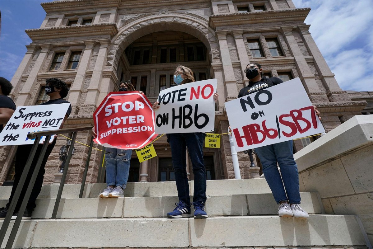 <i>Eric Gay/AP</i><br/>People opposed to Texas voter bills hold signs during a news conference hosted by Texas Rising Action on the steps of the State Capitol in Austin
