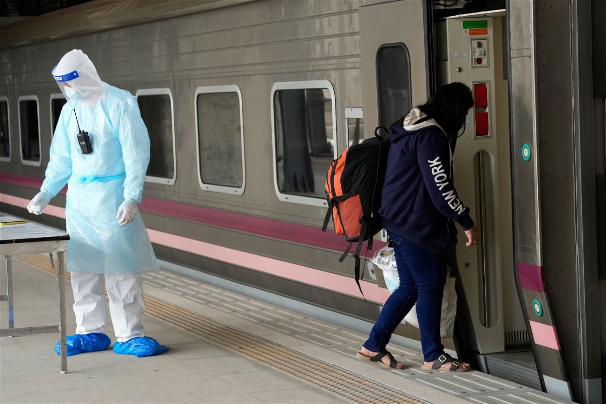 <i>Sakchai Lalit/AP</i><br/>A Covid-19 patient boards a train at Rangsit station on the outskirts of Bangkok to head to her hometown on July 27.
