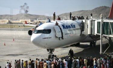 Afghan people climb atop a plane as they wait at the Kabul airport on Monday
