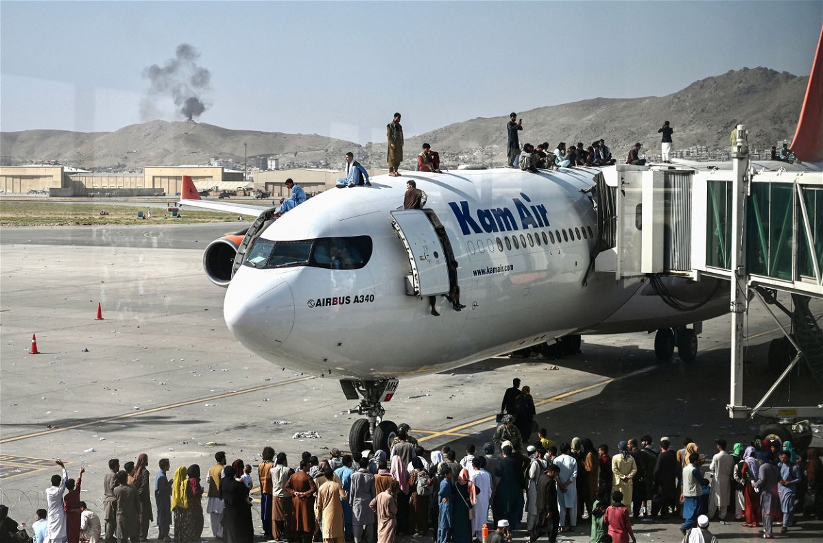 <i>Wakil Kohsar/AFP/Getty Images</i><br/>Afghan people climb atop a plane as they wait at the Kabul airport on Monday