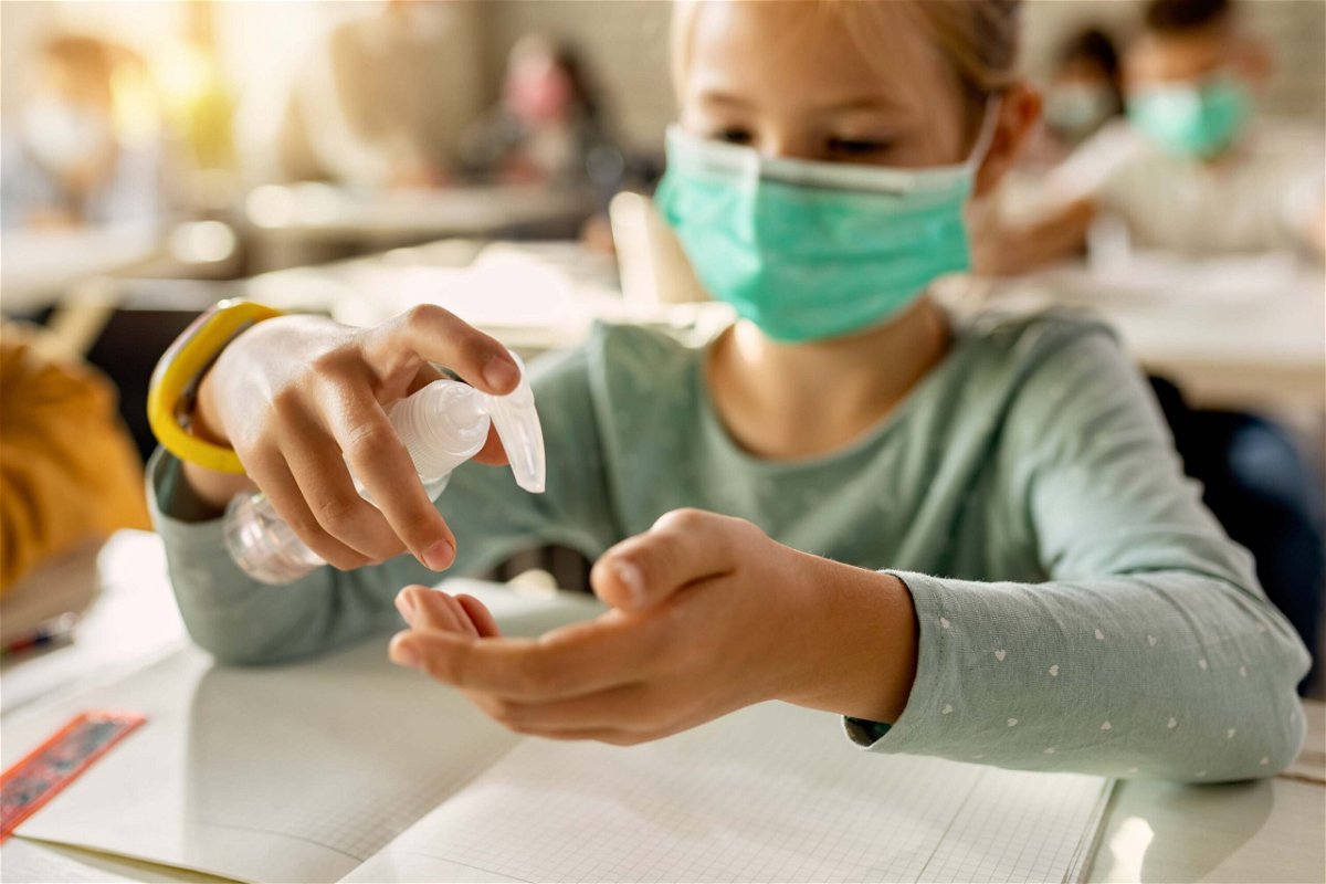 <i>Shutterstock</i><br/>Close-up of elementary student disinfecting hands in the classroom due to COVID-19 pandemic. Protecting children from getting Covid-19 can help everyone in the long run
