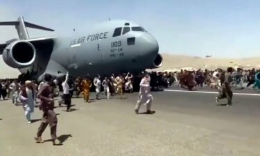 Hundreds of people run alongside a U.S. Air Force C-17 transport plane as it moves down a runway of the international airport