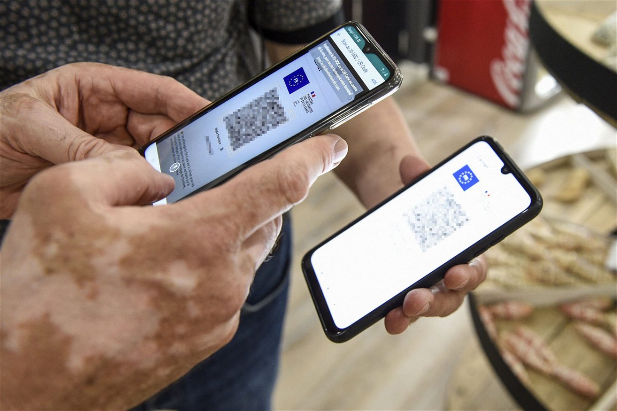 <i>JEAN-CHRISTOPHE VERHAEGEN/AFP/AFP via Getty Images</i><br/>A person uses a pass verification application on a smartphone to check a health pass displayed on a smartphone in Amneville