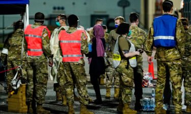 People flown out of Afghanistan leave a transport bus at Ramstein Air Base and are met by soldiers and helpers.