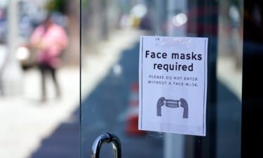 A sign advises shoppers to wear masks outside of a store on July 19 in the Fairfax district of Los Angeles.