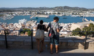 Tourists take in views of the port of Ibiza from the top of the Old Town on July 16.