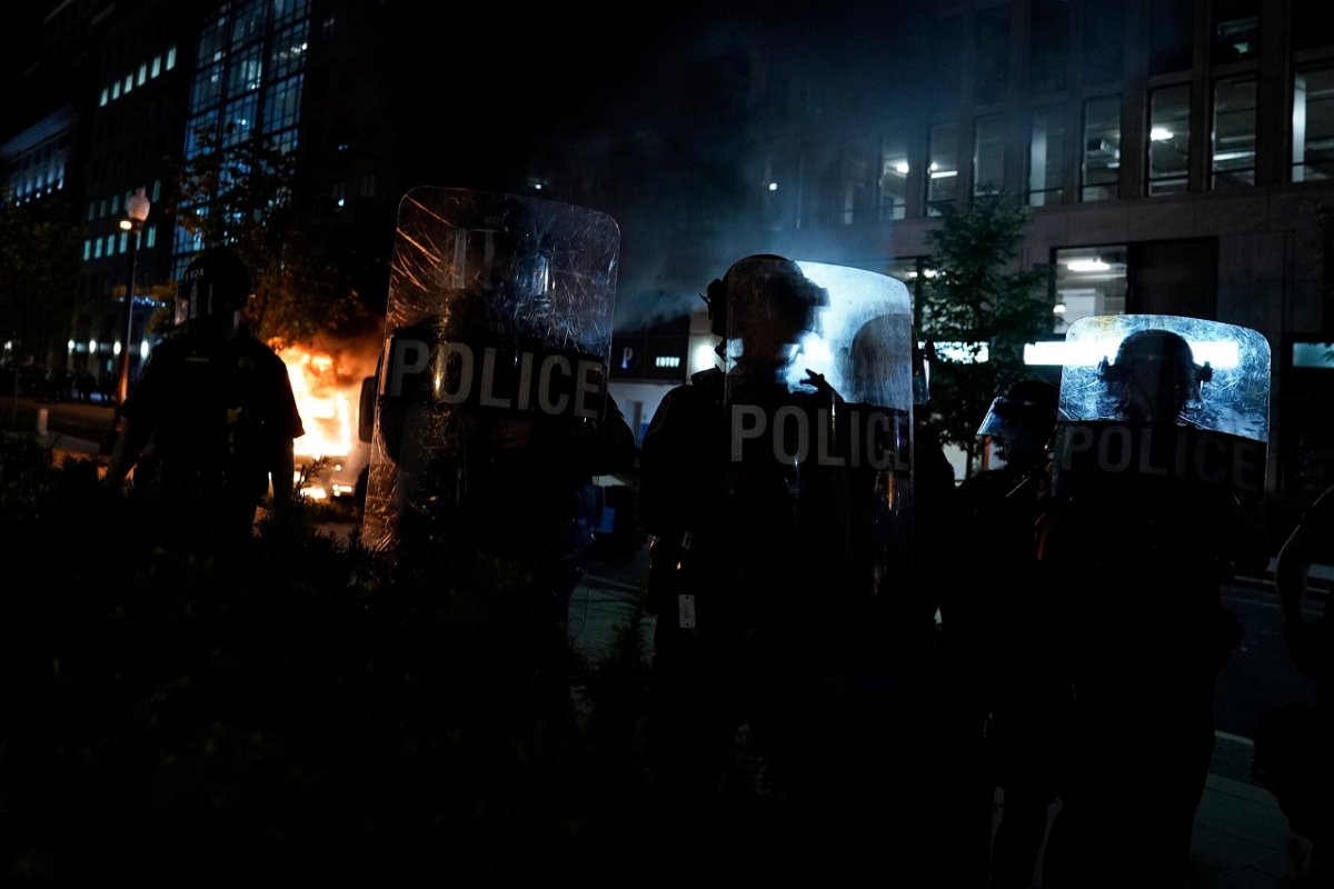 <i>Evan Vucci/AP</i><br/>Police in riot gear watch as demonstrators gather to protest the death of George Floyd in May 2020 in Washington