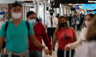 People wearing protective masks walk through Hartsfield-Jackson Atlanta International Airport.