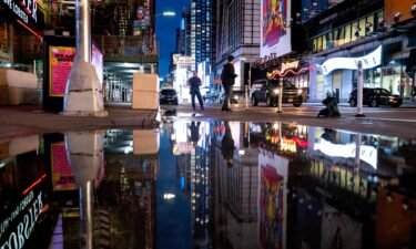 The lights of Times Square in New York are reflected in standing water Thursday