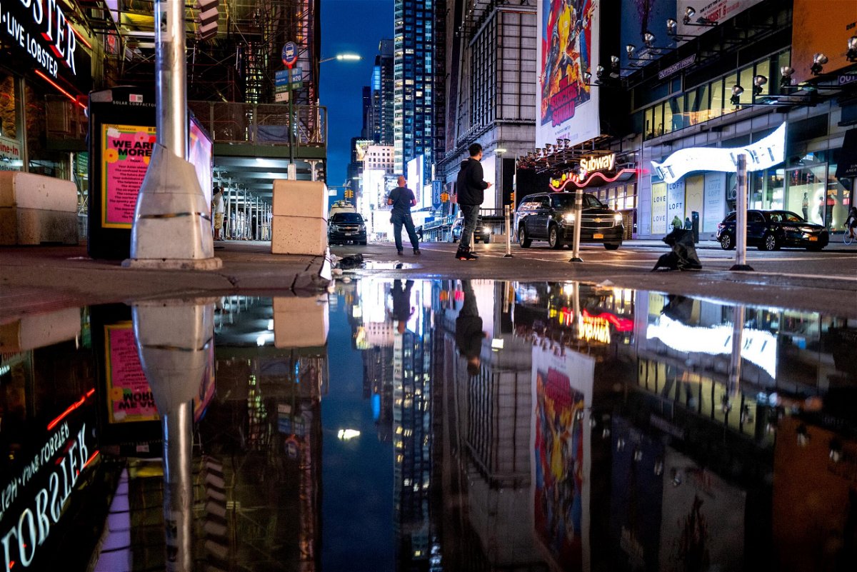 <i>Craig Ruttle/AP</i><br/>The lights of Times Square in New York are reflected in standing water Thursday