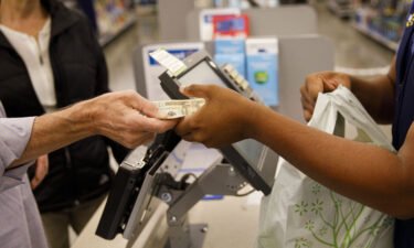 A customer hands cash to an employee while making a purchase at a Walmart location in Burbank