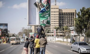 Supporters of Hakainde Hichilema remove a poster of former president Edgar Lungu from a pole in Lusaka